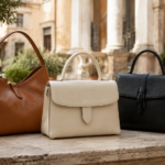 Tre borse in pelle color cuoio, crema e nero su un tavolo in un cortile romano